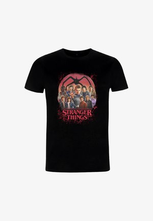 Sort bomulds-T-shirt med grafiktryk af figurer fra "Stranger Things" i farver, med rød tekst og et baggrundselement.