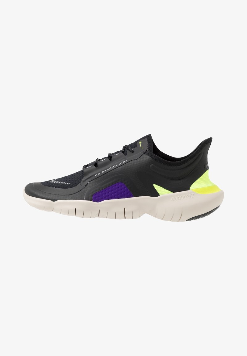 Scarpa da corsa Nike nera e viola con suola bianca, accenti del tallone giallo neon e tomaia testurizzata etichettata "Nike Run Utility Shield."