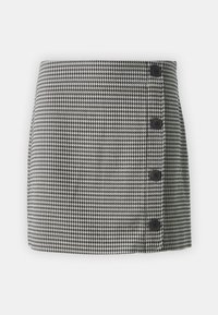 Krilo s houndstooth vzorcem v črni in beli barvi, s pravim krojem, štirimi črnimi gumbi na levi strani in gladko teksturo tkanine.