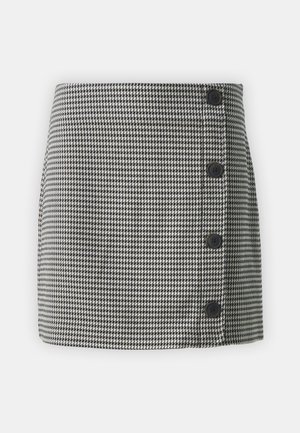 Mustristiga seeliku mustriga mustas ja valges, sirge kujuga, vasakul küljel neli musta nuppu ja siledast kangast tekstuur.