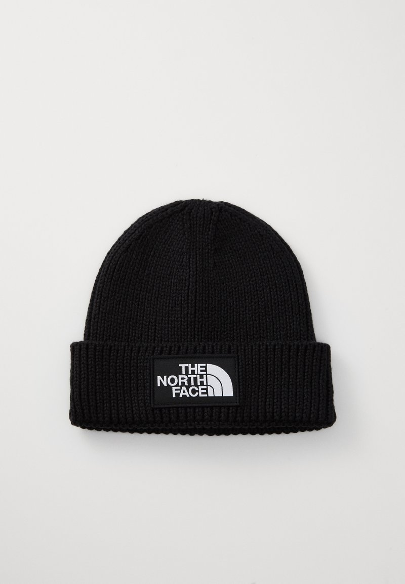 Svart stickad mössa med vikbar muddkant, med en rektangulär logotypapplikation som visar "The North Face" i vitt på en svart bakgrund.