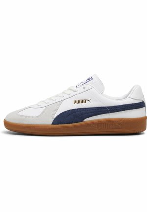 Zapatillas blancas con un acento de ante marino, con una suela de goma y un sutil branding dorado. Diseño de cordones con un cuello acolchado.