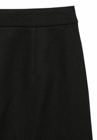 Jupe noire en tissu texturé. Elle présente une taille lisse et des plis avant subtils. Le tissu semble dense et structuré.