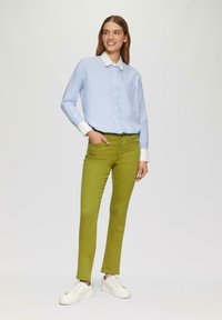 Valkoinen kauluksen kevyesti sininen nappipaidan yhdistelmä, joka on yhdistetty slim-fit vihreisiin housuihin ja valkoisiin tennareihin. Liukkaat tekstuurit ja räätälöity ilme.