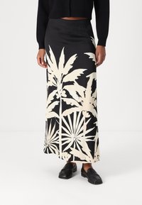 Maxi rok met bloemenpatroon in zwart en crème, gemaakt van zachte stof. Heeft een aansluitende tailleband en een luchtige silhouet.