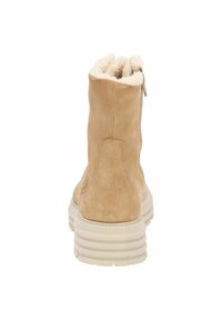 Botín de ante marrón claro con un forro de crema suave y una suela blanca estriada. Presenta una cremallera lateral para facilitar su uso.