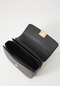 Black leather handbag with a smooth texture, gold-tone hardware clasp, and two compartments for organization. Opened view, minimalistic design.