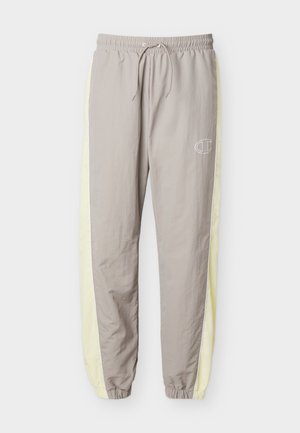 Pantalon de sport gris clair avec taille et poignets élastiques, bandes latérales jaune pâle et petit logo blanc sur la cuisse droite.