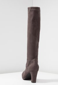 Bota de ante gris hasta la rodilla con forma cónica, tacón de aguja y un detalle de hardware circular en el tobillo. Textura mate en toda su superficie.