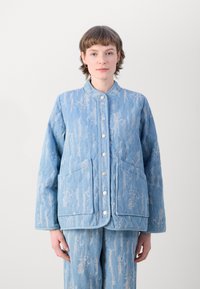 Giacca blu trapuntata con motivo strutturato, colletto rotondo e bottoni argentati. Presenta due tasche frontali e pantaloni abbinati con lo stesso motivo.