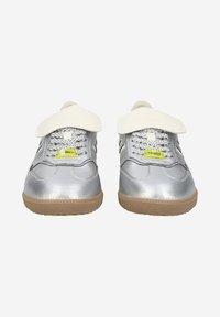 Baskets argentées métalliques avec une surface texturée, dotées d'une languette blanche, de boucles pour les lacets en plastique et d'une semelle en caoutchouc gomme. Accentué d'une étiquette néon.