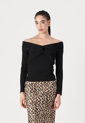 Black off-the-shoulder long-sleeve top with gathered detail in the front, paired with a leopard-print skirt. Smooth fabric texture.