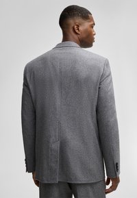 Grau wollener Blazer, strukturiertes Design, Reverskragen, einzelner Rückenschlitz und geknöpfte Manschetten. Textilstruktur mit taillierter Passform.