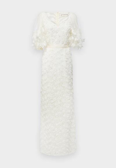 Vestido branco com textura floral, decote em V e mangas bufantes transparentes. Cinto de cetim na cintura. Aplicações florais no tecido adicionam dimensão.