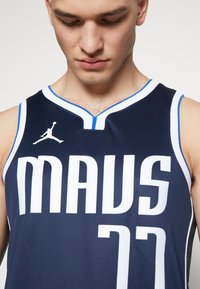 Marine basketballtrøje i navy, med stort hvidt skrift "MAUS" og nummer "77", med blå og hvid kant og Jordan-logo på brystet.