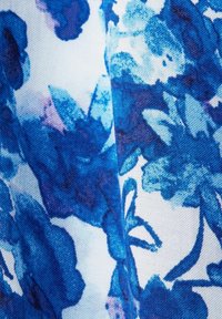 Blommigt tyg i blå nyanser med varierande blå toner, med abstrakta blomstermönster på en vit bakgrund och en strukturerad väv.