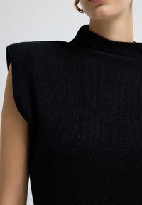 Schwarzes geripptes Top mit strukturierten Schulterpolster, hohem Halsausschnitt und subtiler Textur mit leichtem Schimmer.