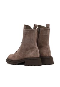 Bruine suède enkelboots met een vetersluiting aan de voorkant, een zijrits en een chunky rubberen zool met een gestructureerd profiel.