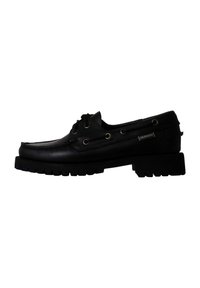 Scarpa da barca in pelle nera con punta arrotondata, lati perforati e suola in gomma spessa. Presenta occhielli dorati e un'etichetta del marchio laterale.