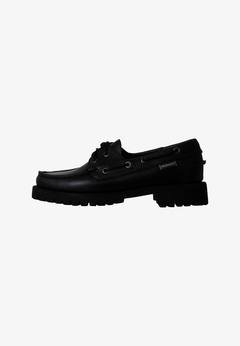 Scarpa da barca in pelle nera con punta arrotondata, lati perforati e suola in gomma spessa. Presenta occhielli dorati e un'etichetta del marchio laterale.