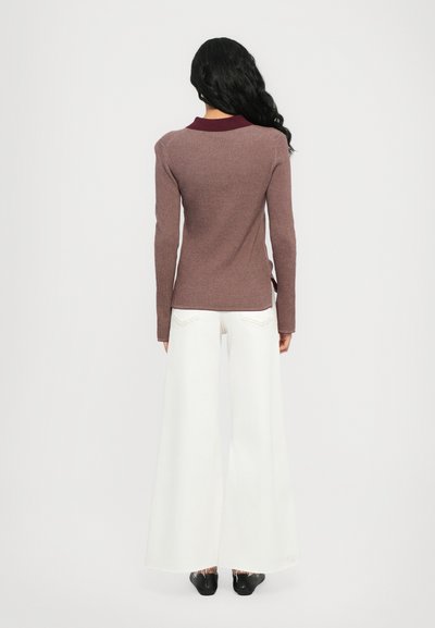 Long-sleeve burgundy collar top in ribbed fabric paired with white wide-leg pants, featuring a straight fit and side slits. Black shoes complete the look.