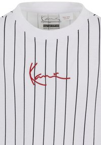 Camiseta blanca con rayas verticales negras, con texto rojo bordado. Cuello redondo y etiqueta que indica la talla 10.