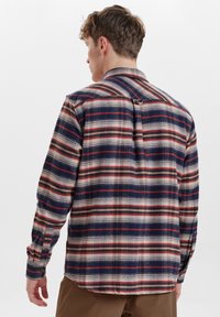 Camisa de cuadros para hombre hecha de franela, con colores azul, rojo y beige. Mangas largas, cuello abotonado y corte relajado.