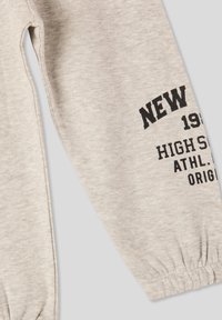 Jasnoszare spodnie dresowe z elastycznymi mankietami, z czarnym nadrukiem "NEW 1979 HIGH SCHOOL ATHL. ORIGINAL." Miękki bawełniany materiał.