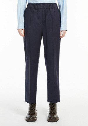 Personne portant un pantalon bleu marine à taille élastique, une chemise à rayures bleu clair à manches longues et des bottines à lacets marron foncé.