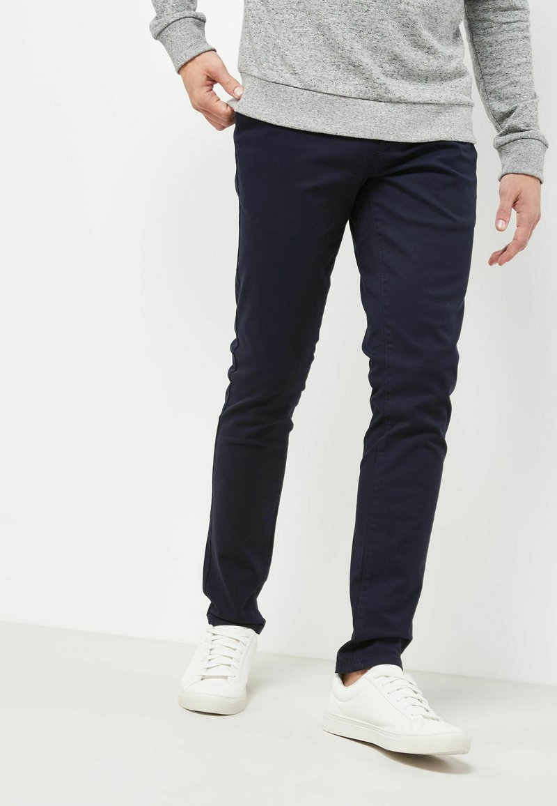 Marineblauwe katoenen broeken met een slim fit, met een gladde textuur, twee zijzakken en gecombineerd met witte sneakers.