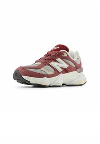 Zapatilla deportiva roja y gris con materiales de malla y ante, que presenta una suela gruesa y acolchada y un logo en el lateral. Punta redonda y diseño con cordones.