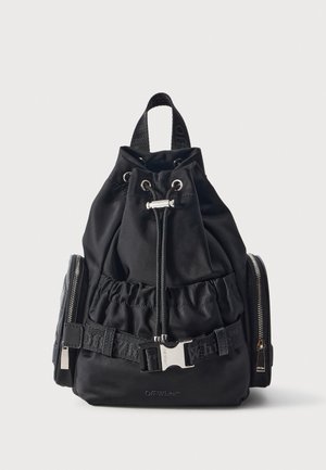 Mochila negra Off-White con cierre de cordón, asa superior, correa delantera con hebilla, herrajes plateados y bolsillos laterales con cremallera sobre un fondo claro.