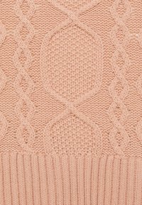 Pull en tricot rose pâle avec des motifs torsadés texturés, un tissage ouvert et un ourlet côtelé. Matière douce et confortable avec des détails complexes.