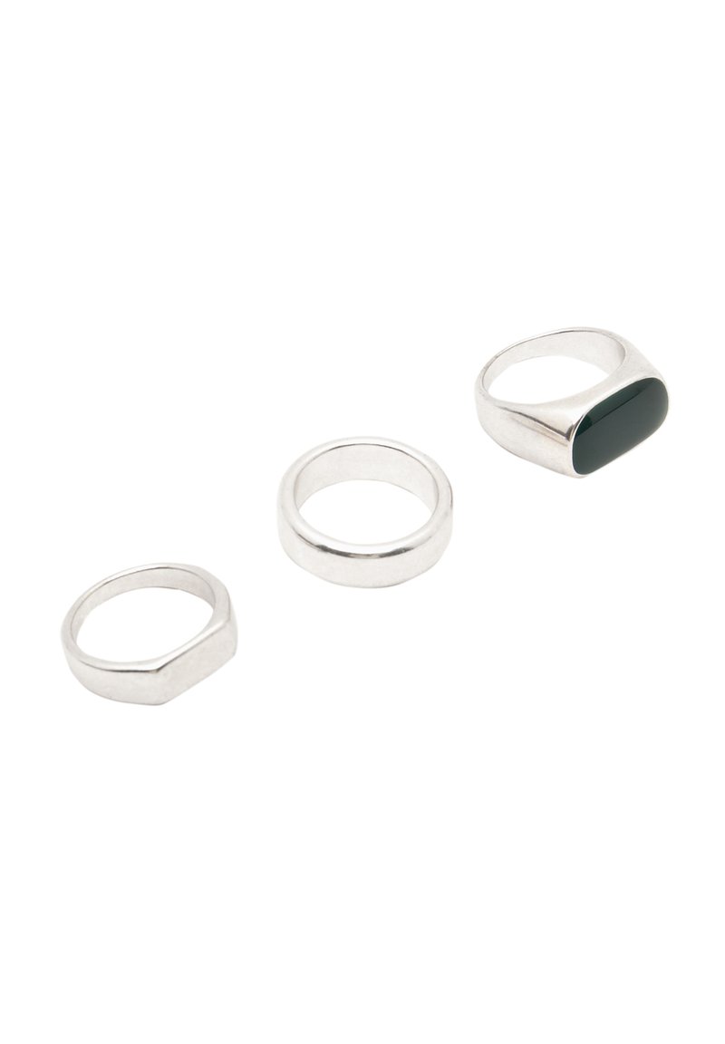 Tre ringar: en hexagonal silverring, en slät silverring och en silverring med en avlång mörkgrön sten.