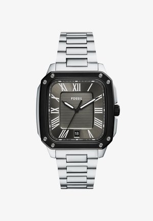 Montre Fossil carrée avec un bracelet en métal argenté. Cadran texturé gris foncé avec des chiffres romains blancs, des aiguilles argentées et un affichage de la date. Boîtier noir.