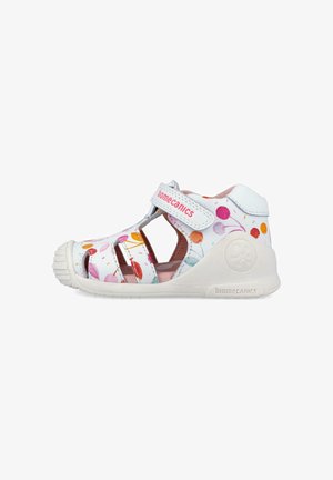 Sandalo chiuso per bambini bianchi con stampa colorata di palloncini, cinturino regolabile con Velcro e suola in gomma di supporto etichettata "biomecanics".