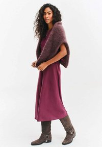 Fioletoworóżowa sukienka o miękkiej fakturze, uzupełniona puszystym, ciemno bordowym szalem. Szare zamszowe kozaki za kolano z ozdobnymi klamrami.