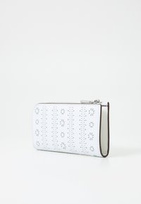 White wallet with cut-out floral patterns, metallic zipper closure, and a structured design. Smooth texture with contrasting edges.