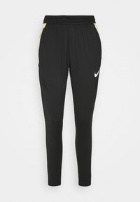 Schwarze Sporthosen mit enger Passform, die gelbe Akzente an den Seiten und ein weißes Nike-Logo aufweisen. Elastischer Bund mit Mesh-Details.