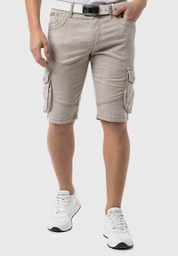 Beige cargoshorts met verticale strepen, zijzakken en een rechte snit. Gecombineerd met witte sneakers en een witte riem.