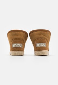 Bottines en suède marron avec une finition texturée, dotées d'une semelle en caoutchouc beige et d'un patch avec logo à l'arrière. Design simple et arrondi.