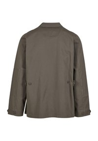 Chaqueta de algodón color verde oliva, con un corte relajado, puños abotonados y un cuello clásico. Presenta una abertura trasera y un bolsillo de parche.