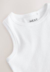 Valkoinen, resorilla varustettu hihaton paita pyöreällä pääntiellä, jossa näkyy sisäetiketti, jossa lukee "NEXT" -brändin nimi.