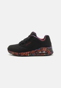 Baskets Skechers noires avec une semelle à motifs floraux, dotées d'un dessus en mesh, d'un col rembourré, d'un système de laçage et d'un coussin d'air visible.