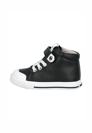 Zapatilla alta de cuero negro con puntera y suela de goma blanca, con cordones y una banda de Velcro, acentuada por un logotipo circular en la banda.