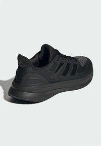 Chaussures de sport noires avec une tige en maille texturée, une semelle en caoutchouc et trois bandes noires sur le côté pour un détail de design.