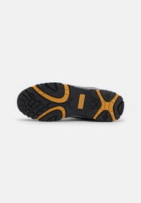 Suola di scarpe in gomma nera con motivi di battistrada aggressivi e linee di accento arancioni, progettata per trazione e durata.