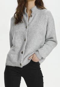 Graue, strukturierte Strickjacke mit langen Ärmeln, hohem Kragen und fünf braunen Knöpfen vorne. Das Material wirkt weich und warm.