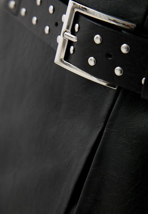 Black leather belt featuring a silver rectangular buckle and row of metallic studs along the strap, displayed against a textured black background.