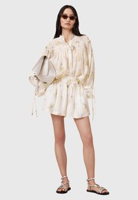 Light floral-patterned blouse and matching shorts in soft fabric, with a drawstring waist and flowing sleeves, paired with silver sandals.
